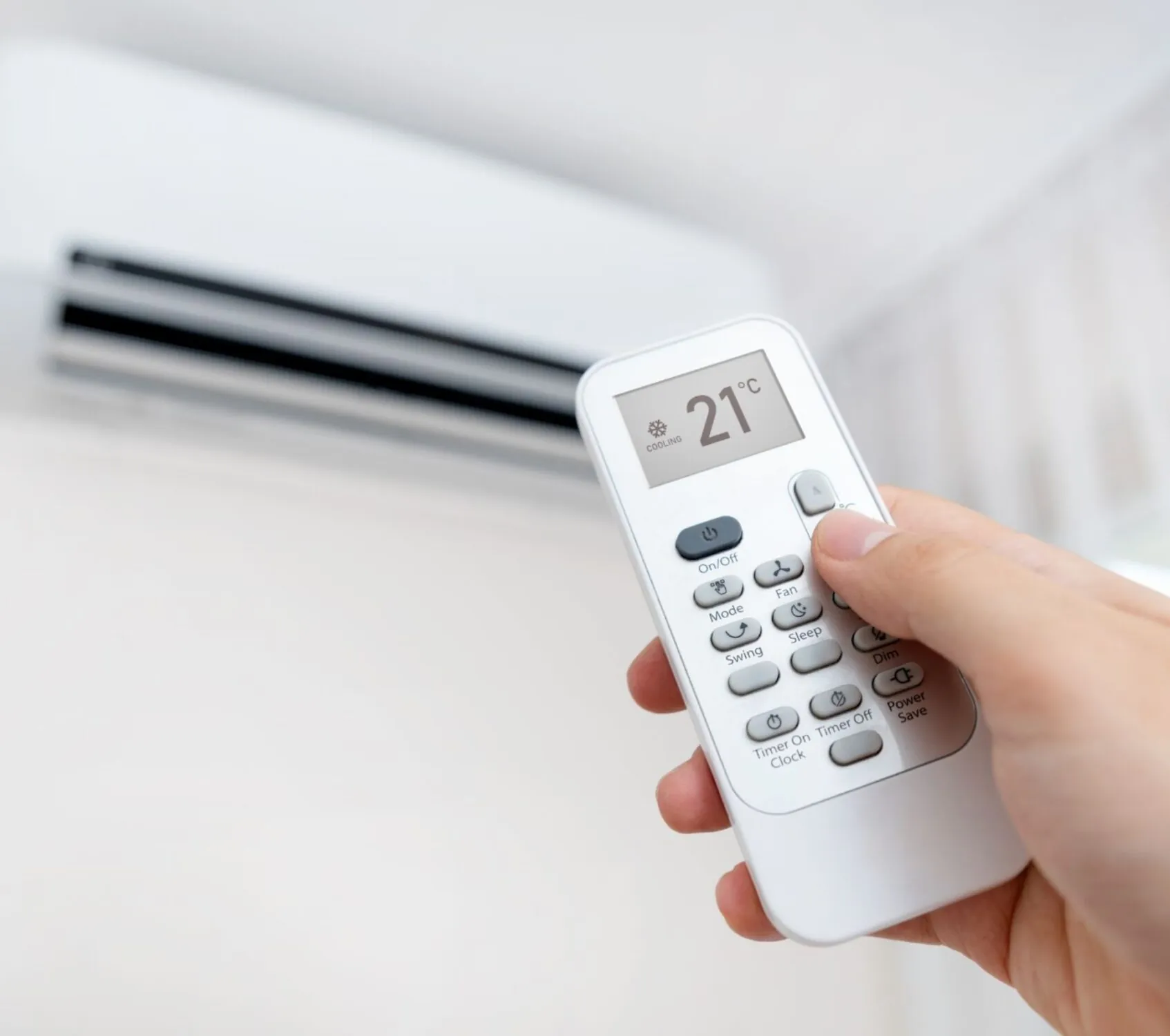 Hand with remote directed on air conditioner