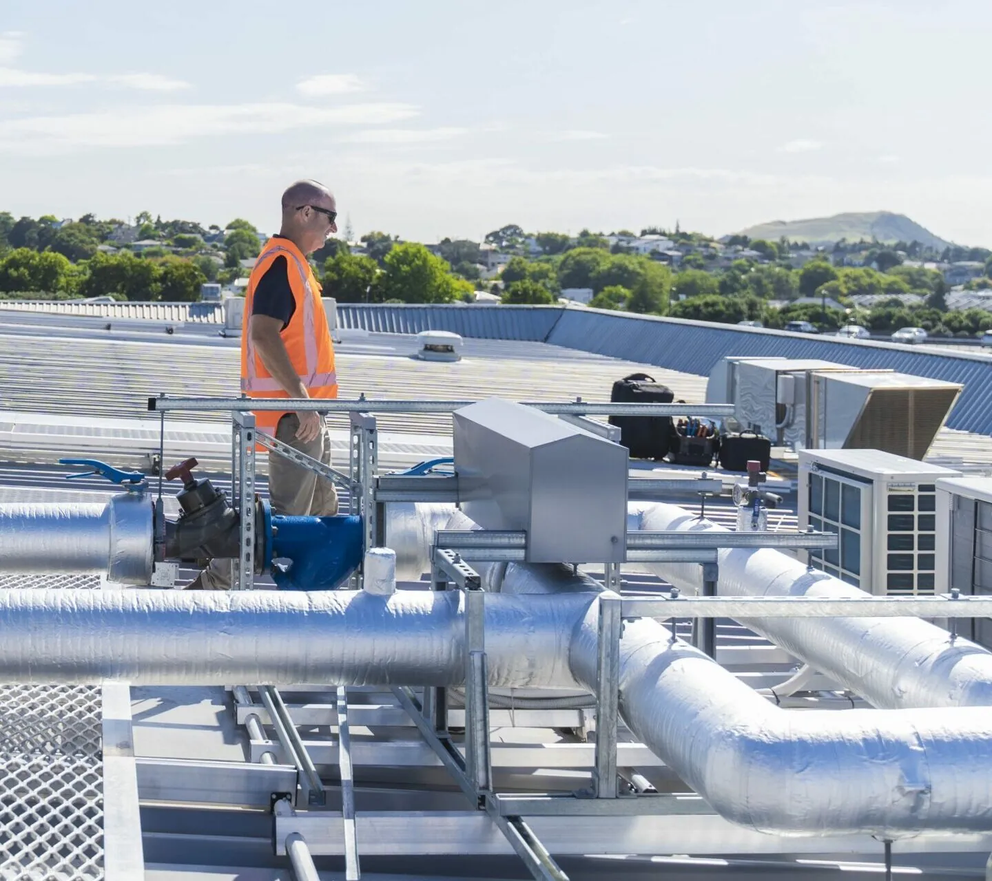 Man inspecting commercial HVAC system on roof
